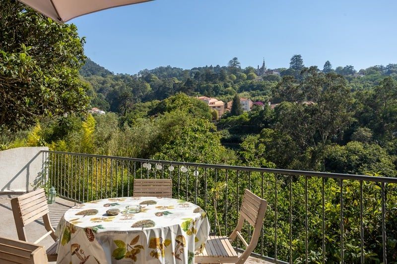 The Studio's own terrace: a table laid under a blue sky, looking out over the valley to the hills and rooftops of Sintra.