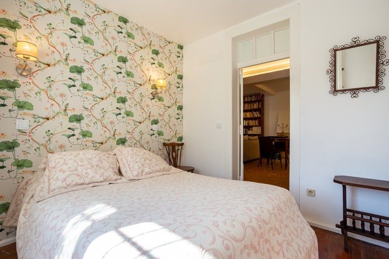 The Birds Room: a double bed against wallpaper of flowering branches, with a doorway through to the library.