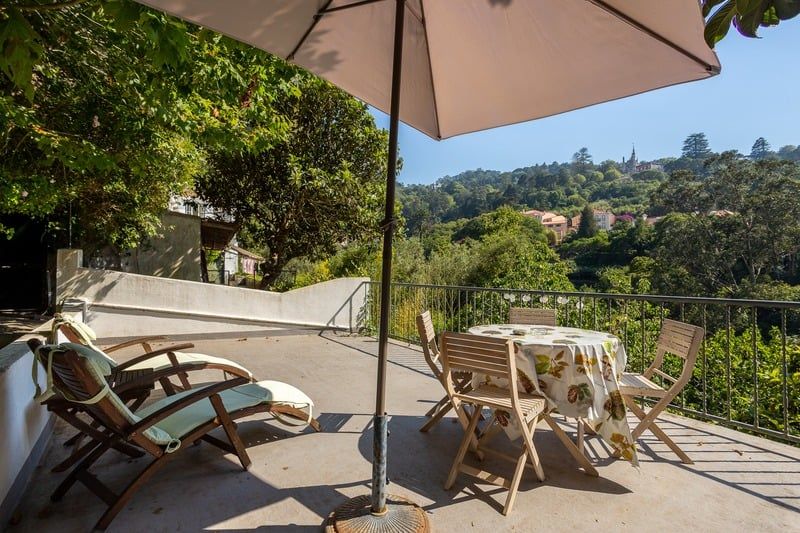 The studio's own terrace: loungers and a parasol on the stone, with the wooded valley beyond the railing.