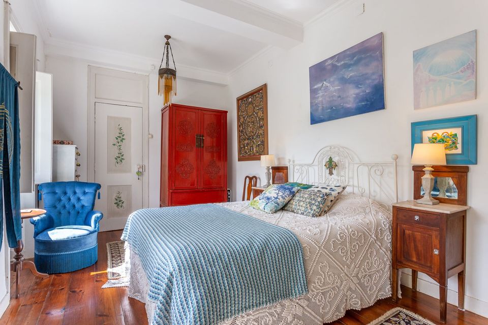 The Blue Room: a double bed dressed in blue against white walls, beside a red lacquered cabinet.