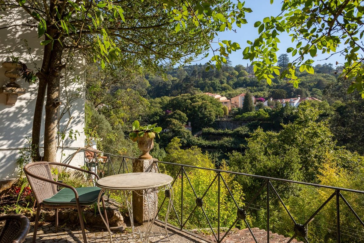 A stone table and two chairs in the garden, in the sun, looking out over the terraced valley.