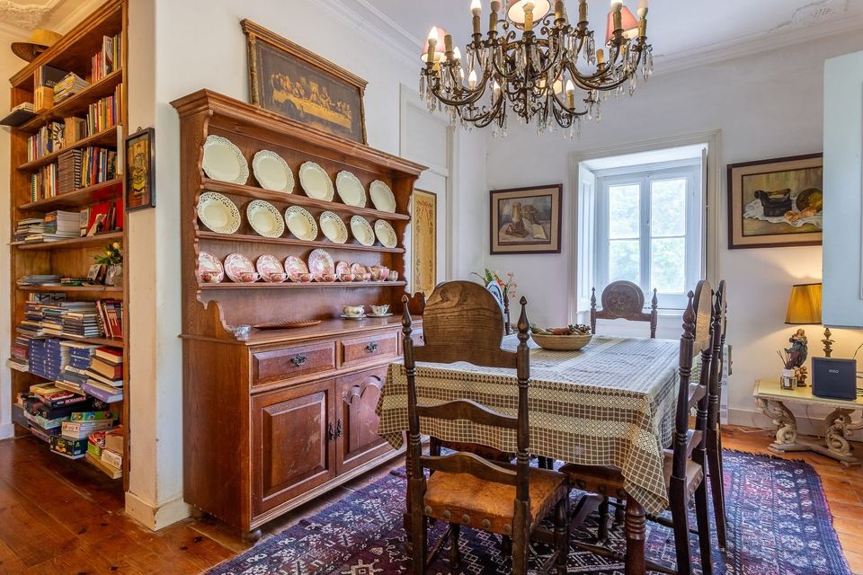 The dining room, with an antique dresser displaying painted plates beneath a chandelier.