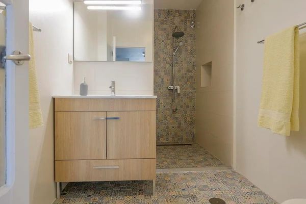 The Yellow Room's fully renovated bathroom, with a timber vanity and a walk-in shower.