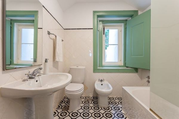 The Twin Room's bathroom in the old style, with a green-framed window and patterned floor tiles.