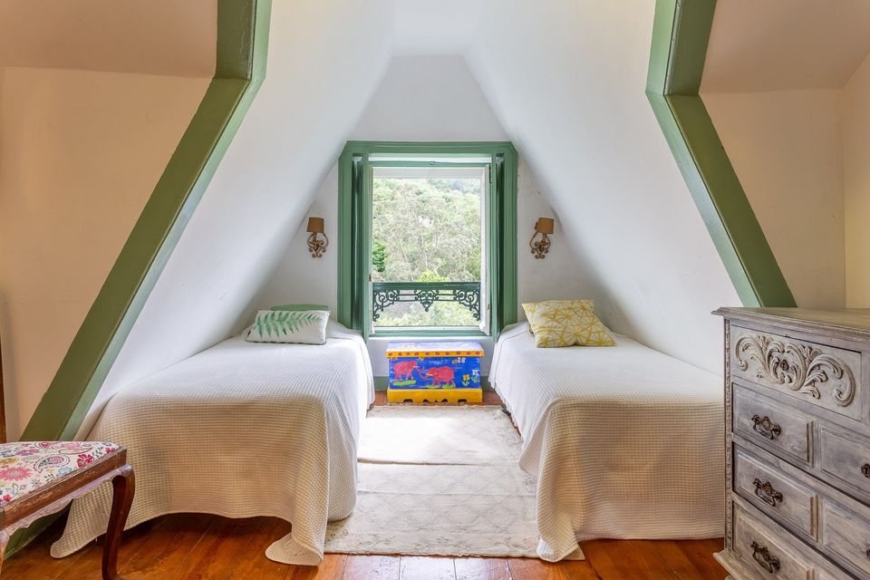 The Twin Room: two single beds under a sloping attic ceiling, beside a green-framed window and a painted toy chest.