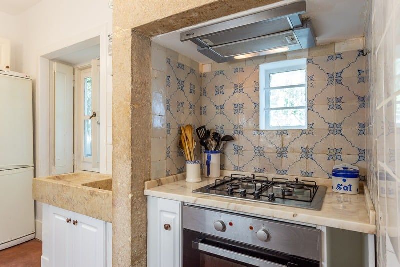 The kitchen, with original 19th-century blue-and-white azulejo tiling behind the hob and a stone surround.